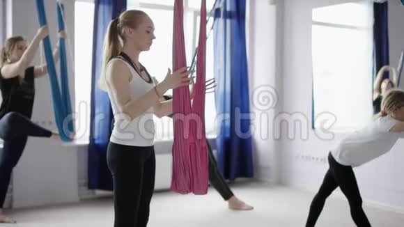 集中精力的年轻女士在瑜伽课上伸展双腿站立并举着长长的东方苍蝇瑜伽吊床视频的预览图