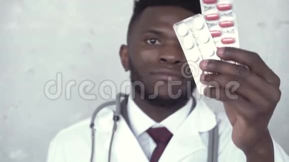 特写黑人男医生的肖像他赞许地点头然后举起两个水泡的红白药丸视频的预览图