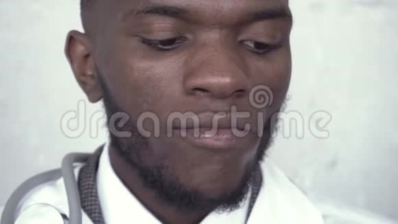 一个穿着白大褂的黑人男医生咬着一块绿苹果嚼着它的脸视频的预览图