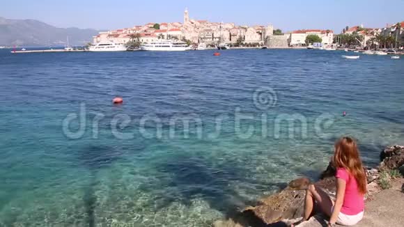 克罗地亚Korcula镇海滨坐着的年轻妇女视频的预览图