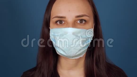 蓝色背景上戴着医用面具的年轻女人的肖像成年女性保护自己免受疾病感染视频的预览图