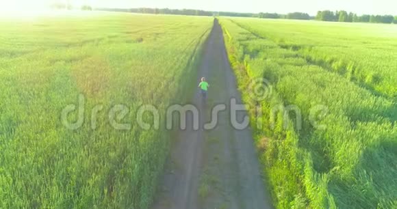 鸟瞰年轻男孩骑着自行车穿过古老的乡村道路上的麦田阳光和光束视频的预览图