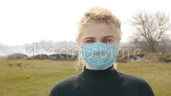 戴着医疗面具穿着黑色毛衣的金发女孩吸烟区环境污染视频的预览图