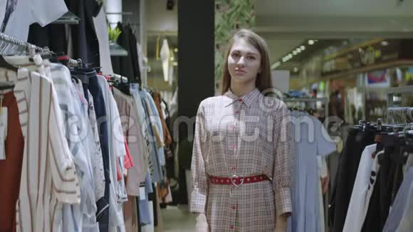 金发微笑的女人正交叉双臂为站在商店里的相机摆姿势一个漂亮的女孩视频的预览图