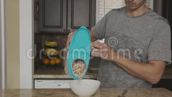 年轻的帅哥从一个塑料罐子里倒出五颜六色的圆形玉米片麦片里面有一个白色的深蓝色盖子视频的预览图