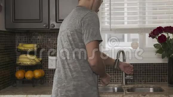 年轻漂亮的男子穿着一件灰色的t恤背对着照相机站着用一个漂亮的盘子或手洗碗视频的预览图