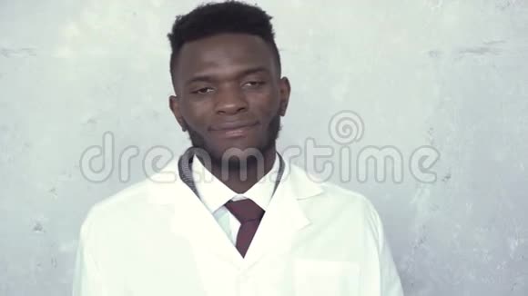 一位穿着白色实验室外套的黑人男医生站在水泥墙上他举起手来视频的预览图