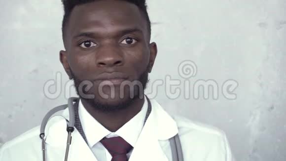 一位穿着白色实验服的黑人男性医生从一只脚移动到另一只脚的正面图像显示摄像机有两个水泡视频的预览图