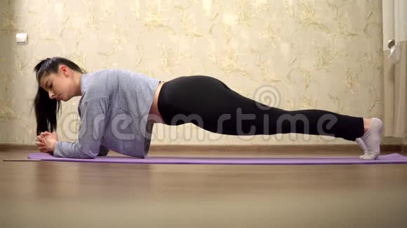 年轻女子在家做运动家庭训练瑜伽练习视频的预览图