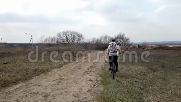 农村骑自行车的年轻女子成年女性休闲装背包骑马时享受大自然视频的预览图
