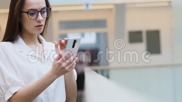 穿时髦商务服装的年轻女性使用智能手机视频的预览图