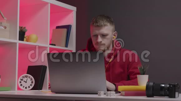 穿红色运动衫的设计师在家里的电脑上工作工作区红色背光视频的预览图