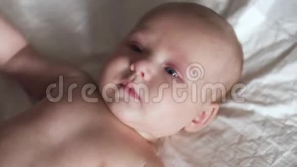 幼儿婴儿躺在床上的尿布上移动他的手微笑试图交谈视频的预览图