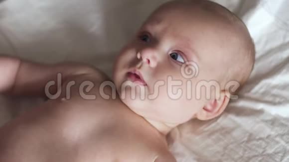 婴儿躺在床上的尿布上移动双手微笑着试着说话视频的预览图