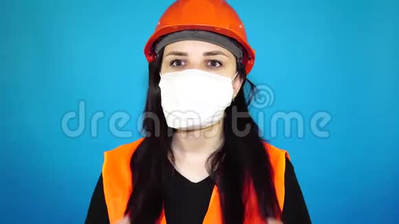 蓝色背景上戴着医用面具的年轻女人的肖像成年女性用面具遮住她的脸视频的预览图