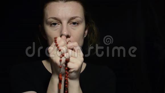 年轻女子在黑暗中用十字架祈祷念珠视频的预览图