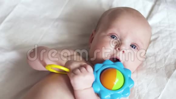 一个新生婴儿躺在餐巾纸上手里拿着一个玩具试图咬它视频的预览图