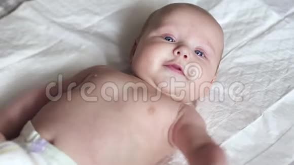 快乐的新生婴儿幼儿在床上微笑并试图交谈视频的预览图