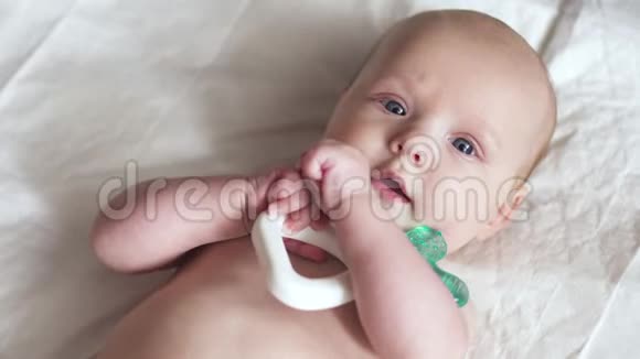 一个新生婴儿躺在餐巾纸上手里拿着一个玩具试图咬它视频的预览图