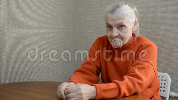 一位孤独的老年妇女坐在桌子旁因负面情绪而伤心地抱着头视频的预览图