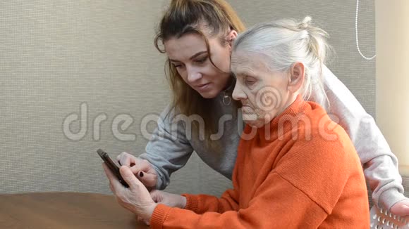 女孙女教年迈的祖母使用智能手机视频的预览图