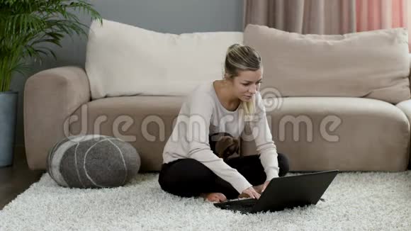 金发女孩坐在笔记本电脑上狗狗在家地毯上视频的预览图