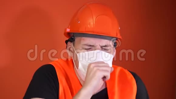 男施工工穿着工作服和医用口罩在橙色背景下咳嗽感染威胁的概念视频的预览图