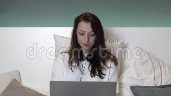 美丽迷人的白种人妇女长发在床上工作的笔记本电脑视频的预览图