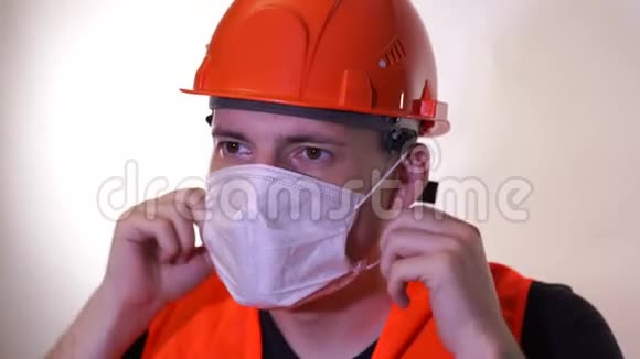男建筑工人穿工作服在白色背景上从脸上摘下医疗面罩视频的预览图