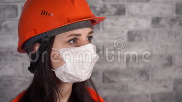 灰色砖墙背景上戴着医用面具的年轻女子的肖像成年女性遮住了她的脸视频的预览图
