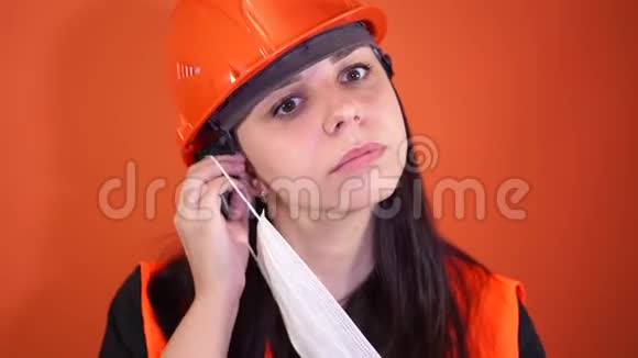 穿工作服的女建筑工人在橙色背景上脸上戴医用口罩视频的预览图