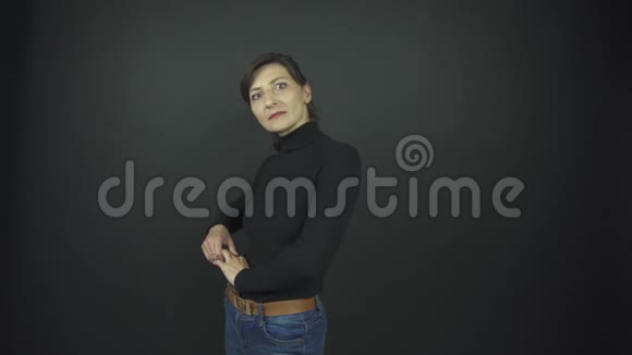 穿着黑色套头衫和蓝色牛仔牛仔裤的漂亮女人视频的预览图