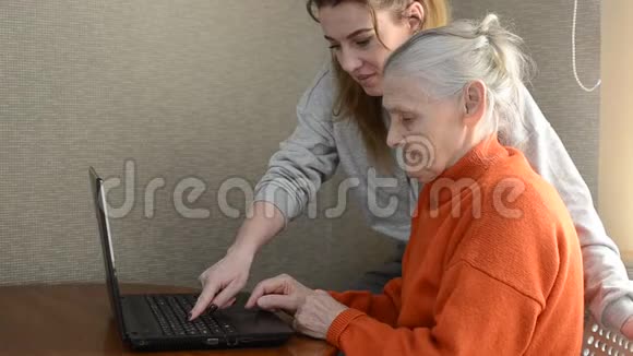 女孙女教她年迈的祖母使用笔记本电脑视频的预览图