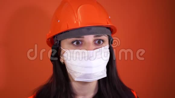 橙色背景上戴着医用面具的年轻女人的肖像成年女性用面具遮住她的脸视频的预览图