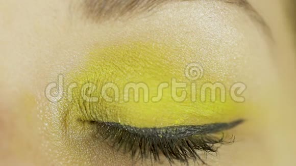 一只绿色的眼睛用黄色的化妆打开眨眼直视相机特写视频的预览图