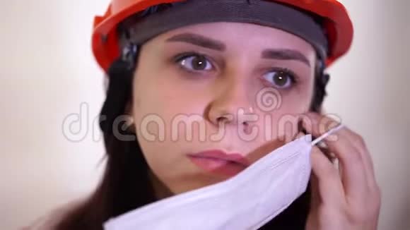 穿工作服的女建筑工人在白色背景上从脸上摘下医疗面罩视频的预览图