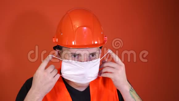 穿工作服的男施工工在橙色背景上脸上戴医用口罩视频的预览图