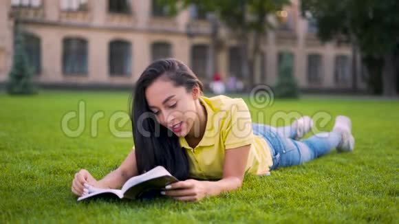 炎热的夏日热情的女孩躺在公园里看书4K视频的预览图