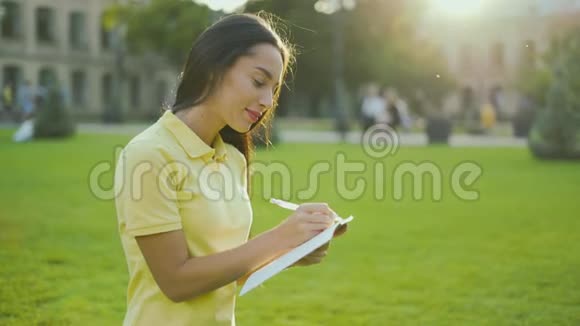女性肖像女人在日落背景上用铅笔在笔记本上写字4K视频的预览图