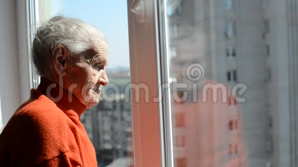 阳光明媚的一天一位老妇人望着窗外视频的预览图