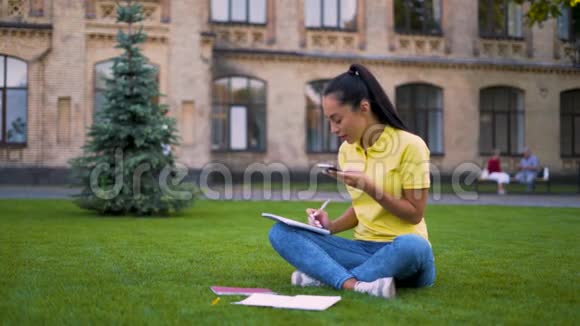 女学生坐在公园的草地上写一条语音留言4K视频的预览图