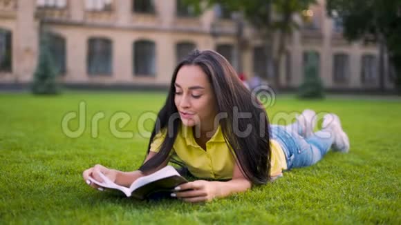 专注的女孩躺在公园里读一本4K的书视频的预览图