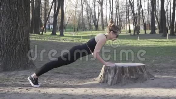 适合女人在树林里锻炼在公园的原木上做俯卧撑在露天自然健身房锻炼俯卧撑吸引力视频的预览图