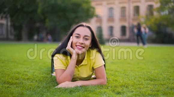 迷人的女孩躺在草地上看着相机4K视频的预览图