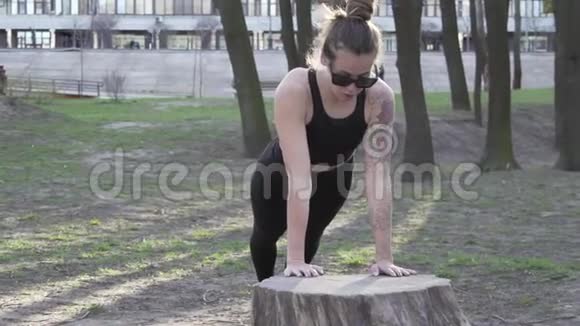 由年轻女性做俯卧撑或俯卧撑锻炼在树林里做俯卧撑的年轻女人女运动员做运动视频的预览图