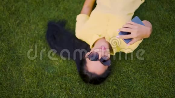 一个开朗的女孩躺在草地上自拍4K视频的预览图