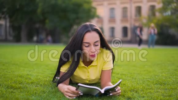 温柔浪漫的女孩躺在公园里读一本4K的书视频的预览图