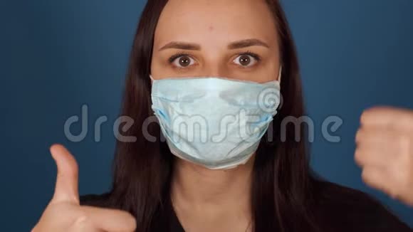 年轻女子戴着医用面具的肖像脸上竖起大拇指成年女性用面具遮住她的脸视频的预览图