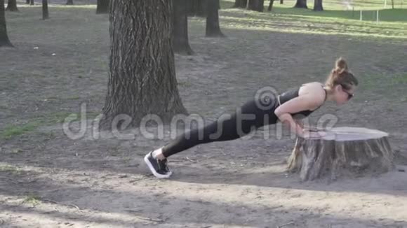 由年轻女性做俯卧撑或俯卧撑锻炼在树林里做俯卧撑的年轻女人女运动员做运动视频的预览图