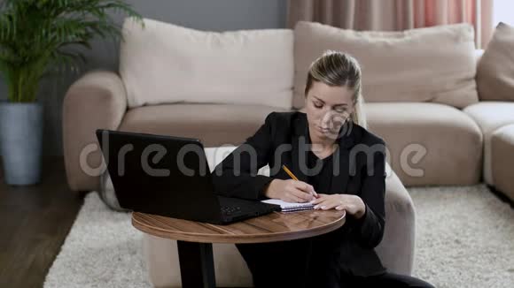 穿黑色夹克的女孩在家里工作笔记本电脑写笔记本视频的预览图